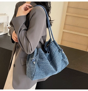 Detail view of the blue denim tote bag texture with knot decor and silver hardware