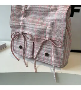 Detailed view of pink plaid fabric texture with ribbon bows and vintage metal buckle