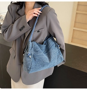 Detail of blue denim hobo bag with knotted shoulder strap and silver metal buckle