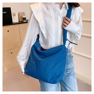 Détail d'un sac bandoulière en nylon bleu marine porté par un mannequin en tenue décontractée