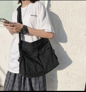Detailed outdoor shot of a black canvas crossbody bag featuring multi-pocket workwear design