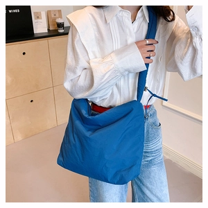 Détail d'un sac bandoulière en nylon bleu avec large sangle et détail de nœud