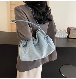 Detailed view of blue denim tote bag featuring decorative drawstring and soft texture