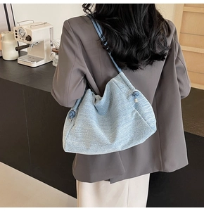 Detailed view of light blue denim shoulder bag with textured fabric on a casual outfit