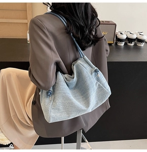 Chic light blue denim tote bag with thick rope straps shown in a stylish urban setting