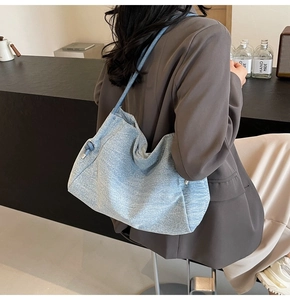 Detailed view of light blue denim tote bag with textured finish and knot strap detail