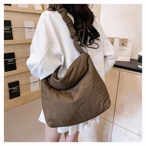 Détail d'un sac bandoulière en nylon olive foncé avec bandoulière froncée et texture nuage