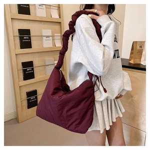 Détail d'un sac hobo matelassé bordeaux en nylon avec grande bandoulière à volants froncés