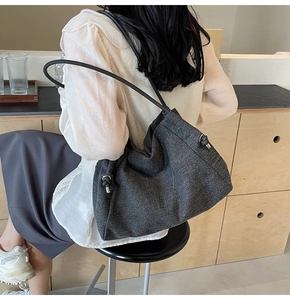 Detail of dark grey textured denim tote bag with silver metallic hardware and shoulder strap
