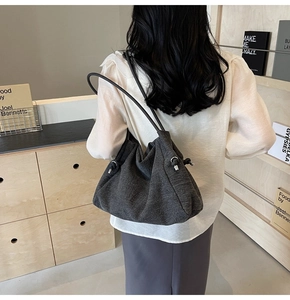 Detailed macro view of dark grey denim tote bag with drawstring closure and silver ring