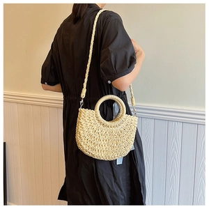 Modella che indossa una borsa a mezzaluna in paglia fatta a mano beige con manico rotondo