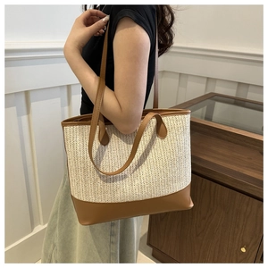 Close-up of woven tote bag featuring cream braided texture and brown leather straps