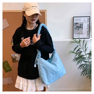 Détail du sac bandoulière matelassé en nylon bleu clair avec cordon sur modèle