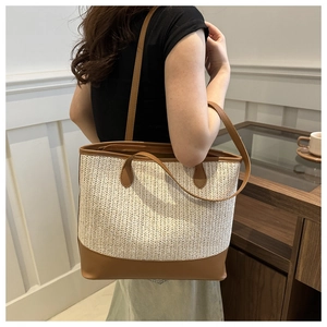 Detail of woven tote bag featuring creamy fabric texture and brown leather base