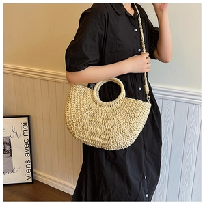 Dettaglio borsa a mano in paglia intrecciata beige con manico tondo e tracolla intrecciata