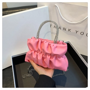 Detail of pink pleated handbag with silver rhinestone handle and metallic chain strap