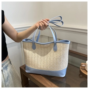 Detail of the woven texture and sky blue leather trim on the summer straw tote bag