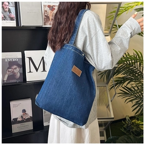 Détail du sac cabas en denim bleu avec étiquette en cuir sur un fond de style de vie