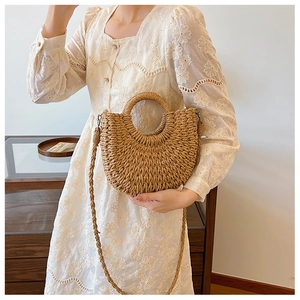 Borsa a mano a mezzaluna in paglia beige con manici intrecciati e abito bianco ricamato