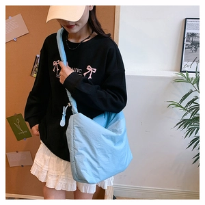 Détail du sac bandoulière en nylon matelassé bleu clair avec sangle rembourrée sur modèle