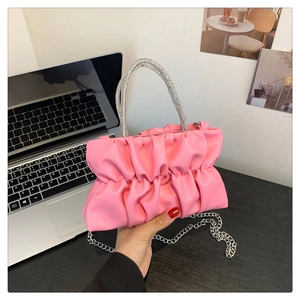 Detail of pink pleated handbag with sparkling rhinestone top handle and silver chain