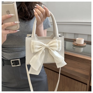 Dettaglio di una borsa in pelle PU bianco crema con grande fiocco decorativo e tracolla