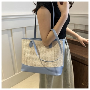 Detail view of woven straw tote bag with sky blue leather trim on female model
