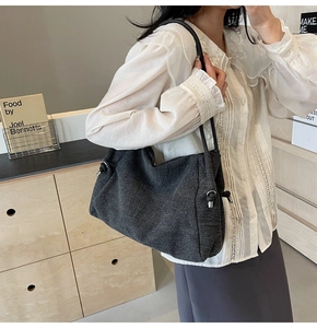 Detail of dark gray denim tote bag featuring side knot design and slim leather shoulder strap