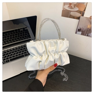 Detailed close-up of white pleated cloud bag featuring sparkling rhinestone handles and chain