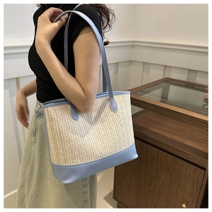 Detail view of woven tote bag showing beige texture and light blue leather handle trim