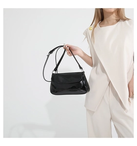 Vue détaillée du sac bandoulière en cuir verni noir avec sangle réglable et fini brillant