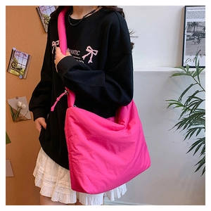 Détail du sac bandoulière nuage en nylon rose vif tendance porté par un mannequin