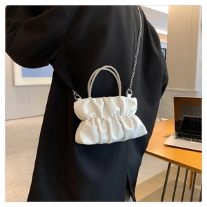 Detail of white pleated cloud bag with crystal encrusted round handles and metal chain strap