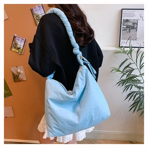 Gros plan du sac nuage en nylon bleu clair avec bandoulière froncée et texture