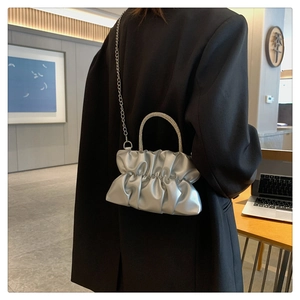 Detail of silver cloud bag with pleated material and rhinestone handle on a shoulder