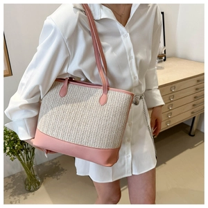 Detail shot of a woven pink and beige tote bag styled with a white shirt dress
