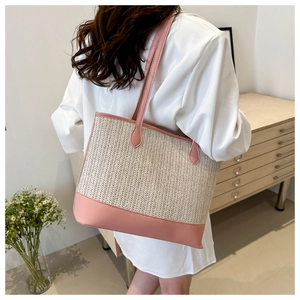 Detail of pink leather trim and beige woven texture on this summer straw tote bag