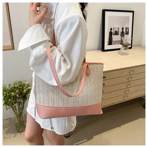 Close-up of woven beige fabric and pink leather trim on a stylish tote bag