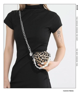 Detail of heart-shaped leopard print bag featuring pearl handle and silver chain strap