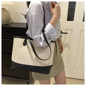 Woven straw tote bag with black leather base shown in a modern lifestyle setting