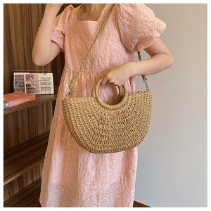 Dettaglio della borsa a mano a semicerchio in paglia intrecciata a mano con texture naturale