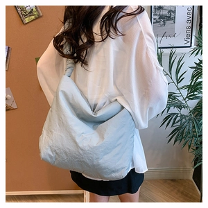 Détail du sac hobo en nylon bleu clair avec texture plissée porté par un mannequin
