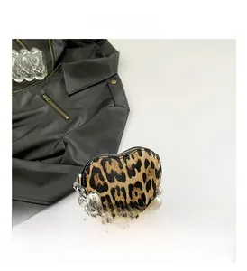 Detail showing leopard print heart-shaped bag with pearl and silver chain accessories