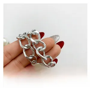 Close-up of thick silver metal chain strap with circular tag on a trendy PU crossbody bag