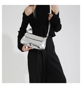Sac baguette argenté effet miroir porté par un mannequin au style très contemporain