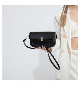 Close-up of minimalist black PU leather crossbody bag with elegant gold metal buckle detail