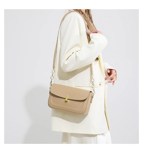 Detail of beige faux leather crossbody bag with elegant gold metal buckle on white suit