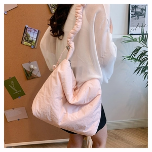 Grand sac bandoulière en nylon matelassé rose avec bandoulière plissée sur modèle