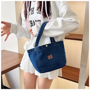 Gros plan du sac en jean bleu avec broderie 23 HITOM et boucle en métal doré chic