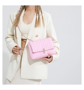 Close-up of pink matelasse quilted leather bag with gold buckle and chain strap